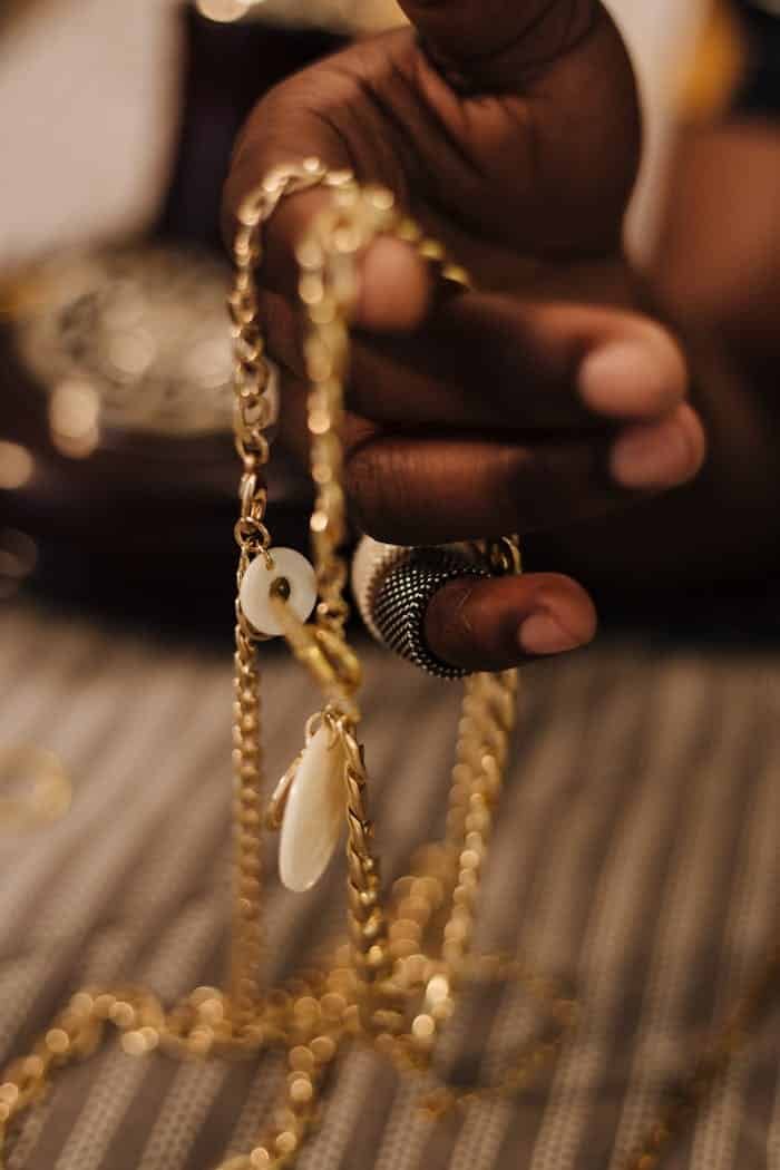 A detailed close-up of a hand holding golden jewelry with selective focus and blurred background.